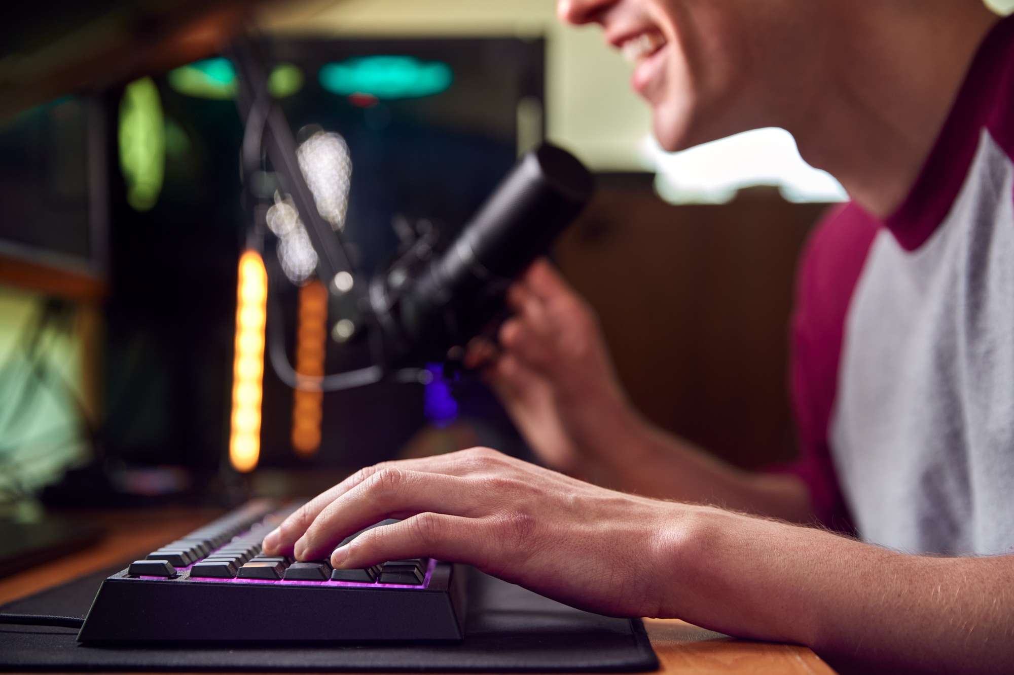 Close Up Of Hands On Keyboard As Man Games At Home Sitting At Desk With Multiple Monitors